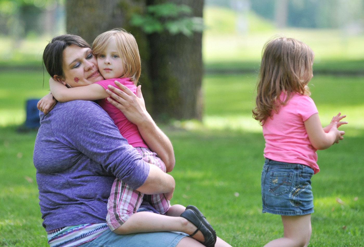 An early childhood caregiver holding a child outdoors during play.