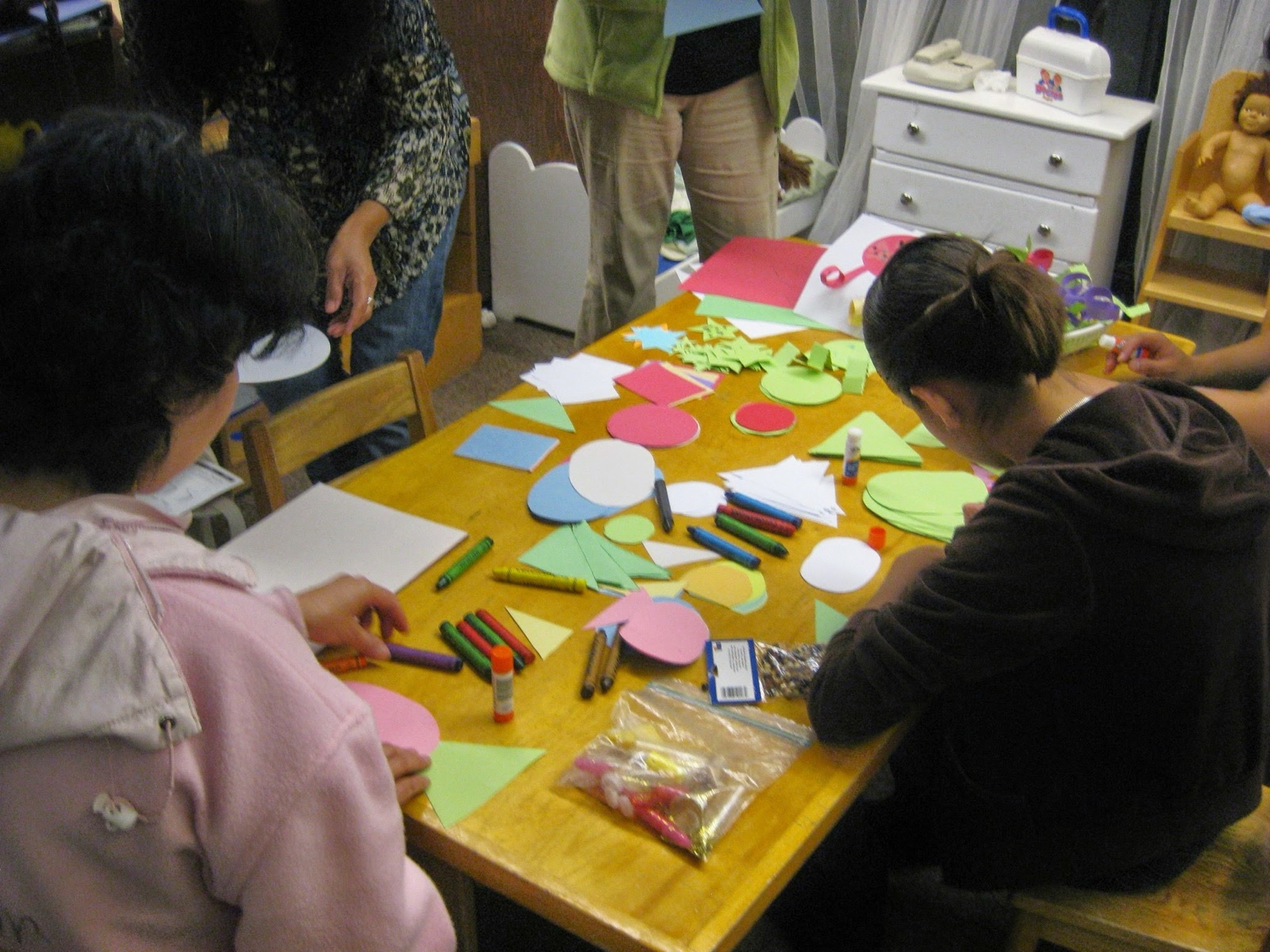 Adult learners working with paper shapes and hands-on materials in an early childhood education curriculum course.