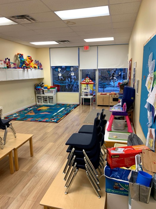 A preschool classroom with child-size tables, shelves, toys, and learning centers.