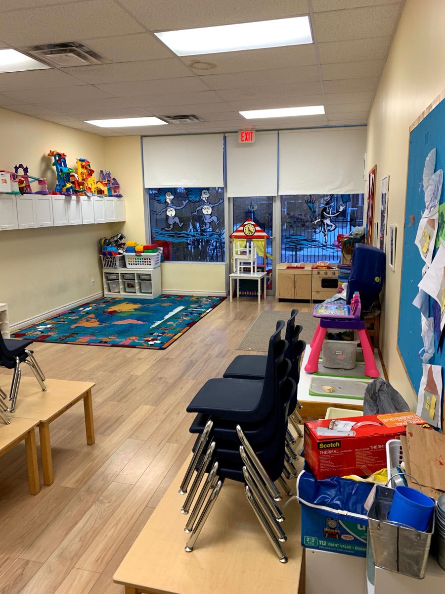 A prepared preschool classroom with child-size chairs, toys, artwork, and learning centers.
